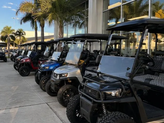 A row of custom lifted golf carts lined up outside a dealership showroom